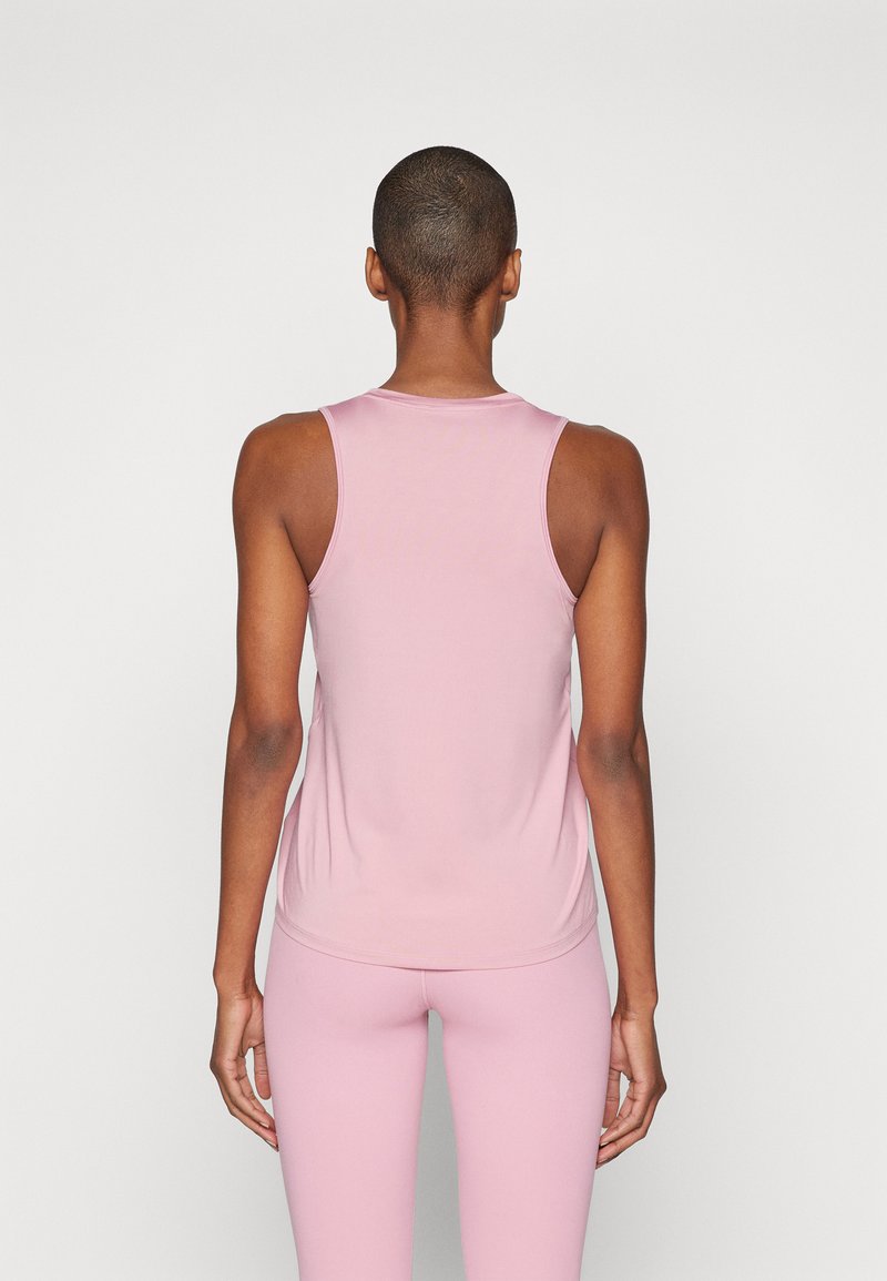 Top sin mangas de color rosa claro con cuello redondo y textura suave, diseño ajustado, combinado con leggings a juego.