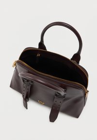 Καφέ δερμάτινη τσάντα με χρυσό φερμουάρ, διπλές λαβές και ρυθμιζόμενους ιμάντες. Το εσωτερικό είναι μαύρο με λείο φινίρισμα. Χρυσές λεπτομέρειες.