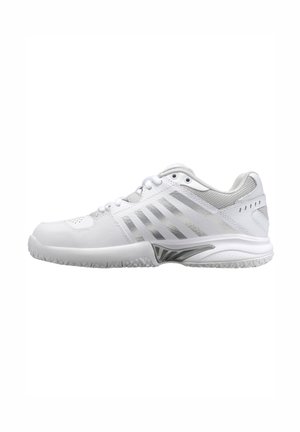 Baskets de sport blanches avec des rayures grises angulaires, talon en mesh, semelle texturée et lacets présentés en profil latéral sur fond blanc.