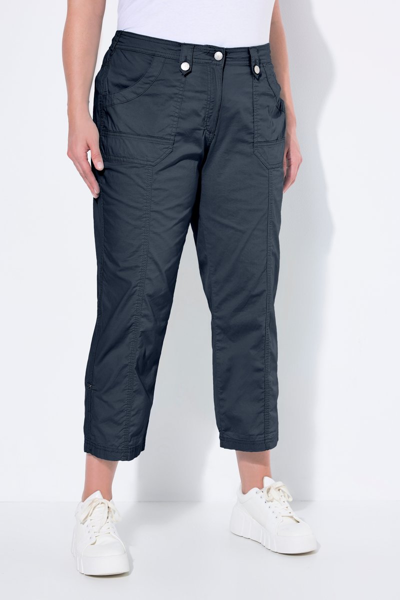Sorte croppede arbejdssbukser med frontlommer med klap, båret med hvide platformsneakers og en hvid top.