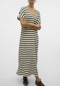 Robe maxi rayée en crème et noir, avec un col en V, des manches courtes, une coupe décontractée et des fentes sur les côtés pour plus de liberté de mouvement.