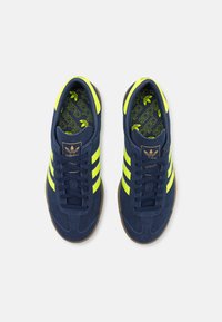 Morske semišne superge z neon rumenimi črtami in poudarki. Imajo oblazinjen ovratnik in teksturiran gumijast podplat. adidas logotip na ježku.