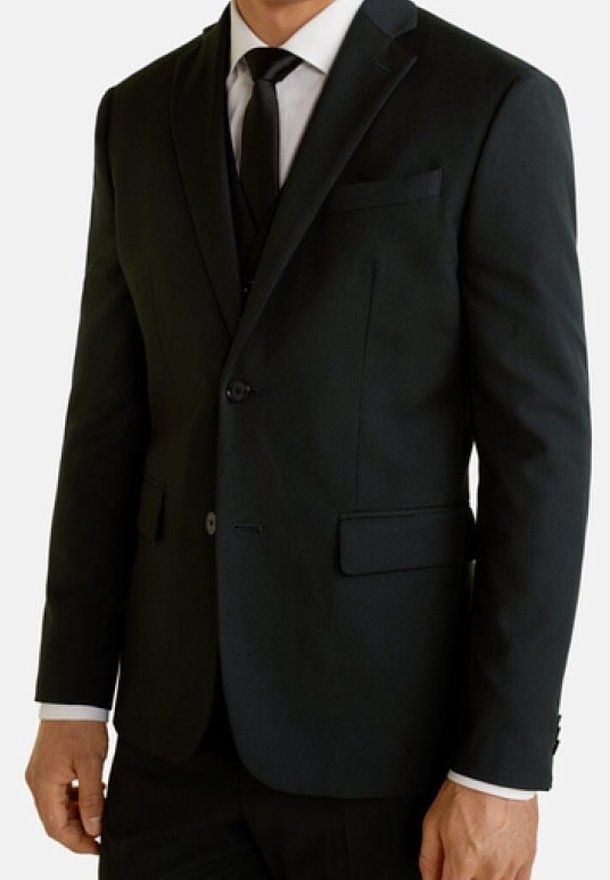 Veste de costume noire avec revers crantés et deux boutons, dotée d'une poche poitrine et de poches latérales. Chemise habillée blanche et cravate noire visibles.