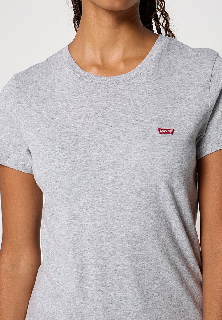T-shirt en coton gris à manches courtes, arborant un petit patch logo rouge de Levi's sur la poitrine. Encolure ronde et texture douce.