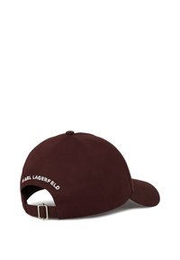 Tamsiai ruda reguliuojama beisbolo kepuraitė su metaline sagtimi ir baltu "KARL LAGERFELD" siuvinėjimu ant nugaros.