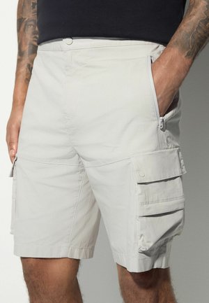 Bermudas cargo grises claras fabricadas con una tela ligera, que cuentan con múltiples bolsillos, un bolsillo con cremallera y un ajuste relajado.
