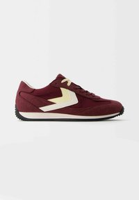 Chaussure de sport bordeaux avec un motif chevron crème, semelle crème et noire, et lacets, vue de côté sur fond blanc.