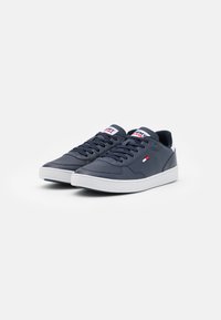 Sneaker in pelle blu navy con suola bianca, dotate di un colletto imbottito, lacci bicolore e un'etichetta con logo sulla linguetta.