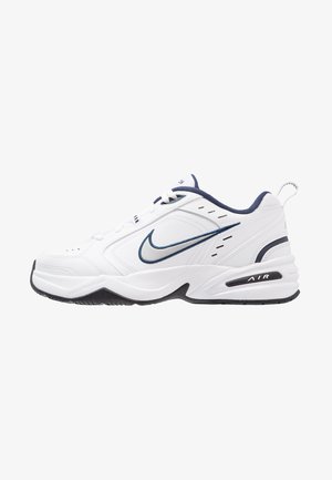 White athletic shoes with a textured leather upper, navy accents, and perforations for ventilation. Features a black rubber sole and air midsole.