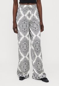 Pantalones de pierna ancha en blanco y negro con un acabado suave y cintura elástica, que presentan diseños intrincados y un estampado geométrico audaz.