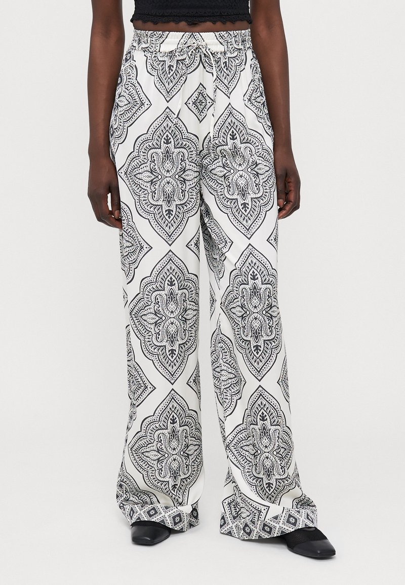 Pantalones de pierna ancha en blanco y negro con un acabado suave y cintura elástica, que presentan diseños intrincados y un estampado geométrico audaz.