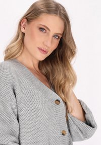 Cardigan gri tricotat, cu decolteu în V, croială lejeră, nasturi din lemn și material texturat cu manșete cu bandă.}}