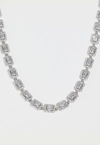 Ασημένιο κολιέ με ορθογώνιες διάφανες πολύτιμες πέτρες, καθεμία περιβαλλόμενη από μικρότερες διάφανες πέτρες, συνδεδεμένες σε έναν συνεχή σχεδιασμό αλυσίδας.