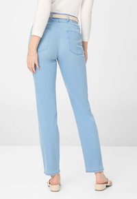 Lyseblå denim jeans med lige ben, der har baglommer og bælteslynger. Stoffet ser blødt ud med en let tekstur.