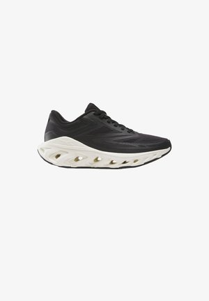 Black low-cut athletic shoe with breathable mesh upper and thick white sole featuring multiple oval cutouts.