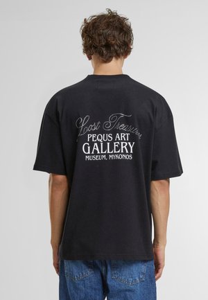 Fekete pamut póló, fehér és fémtűz-hatású ezüst szöveggel a hátsó részén, laza fazonnal és rövid ujjakkal. A szöveg tartalmazza a "Lost Treasure" és a "Pegu Art Gallery" feliratokat.
