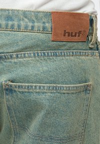 Φωτεινά μπλε τζιν από τζιν ύφασμα με υφή, με καφέ ετικέτα από δερματίνη με ανάγλυφο το "huf" στη μέση.