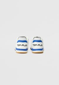Scarpe atletiche bianche con accenti blu, tessuto perforato sulla parte superiore e suole in gomma. Logo "TOP-FLEX" sul tallone.