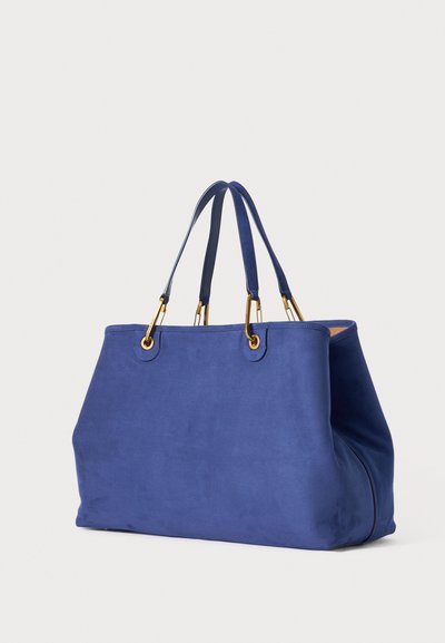 Sac fourre-tout en daim bleu avec deux poignées supérieures et des accents en métal doré. Caractérisé par une forme spacieuse et structurée ainsi qu'une texture lisse.