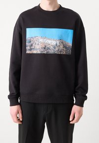 Černá mikina s grafikou svahu a bílým nápisem "HUGO WOOD". Kulatý výstřih a žebrované manžety.