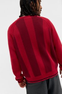 Camisola vermelha de malha com riscas horizontais num tom mais escuro de vermelho. Punhos e bainha em malha canelada, corte descontraído e superfície texturada.