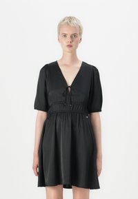 Vestido preto feito de tecido liso, com decote em V, la�ço frontal, mangas curtas bufantes e cintura elástica.