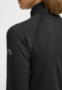 Zwart sporttop van gladde, rekbare stof, met een hoge kraag, lange mouwen en een klein grijs logo op de schouder.