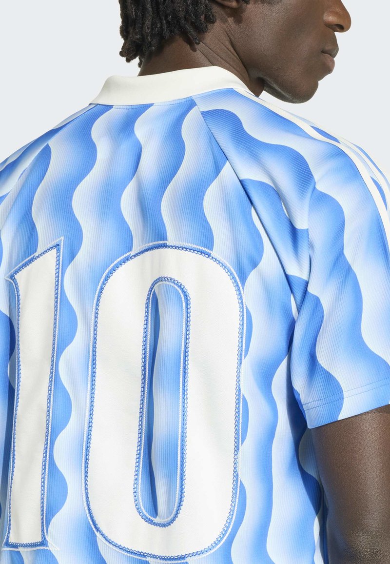 Mann trägt ein blau-weiß gestreiftes Sporttrikot mit wellenförmigen Streifen und der Nummer 10 auf dem Rücken, von hinten gezeigt und leicht seitlich gedreht.