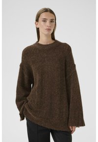 Bruine oversized trui met een textuur en een pluizige afwerking, met verlaagde schoudernaden en een ronde halslijn.