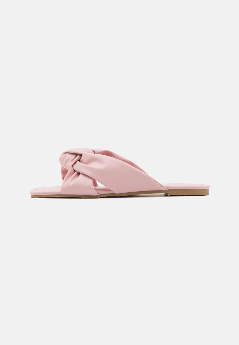 Sandale plate pour femmes avec des lanières roses rembourrées torsadées et une semelle brun clair, présentée de côté sur un fond blanc.
