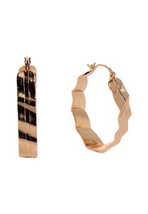 Kolczyki koła z metalu w złotym kolorze o skręconym, falistym wzorze i zamknięciu na zawiasach na białym tle.