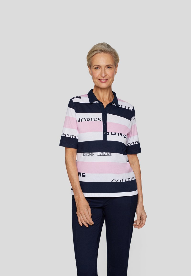 Poloshirt mit Kragen im gestreiften Muster, das Rosa, Weiß und Marineblau enthält. Textdrucke sind über die Streifen verteilt. Kurze Ärmel.