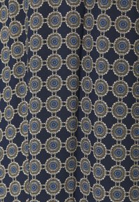 Tissu bleu marine avec un motif complexe de médaillons dorés et bleus, à la finition texturée et aux accents détaillés.