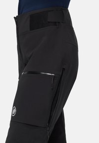 Μαύρο εξωτερικό παντελόνι κατασκευασμένο από ανθεκτικό υλικό, με τσέπη πλευρικής φερμουάρ και ρυθμιζόμενη μέση με κλείσιμο από βέλκρο.