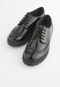 Schwarze Lacklederschuhe im Brogue-Stil mit Schnürung, dekorativen Durchbrüchen, runder Spitze und einer dicken Gummisohle.