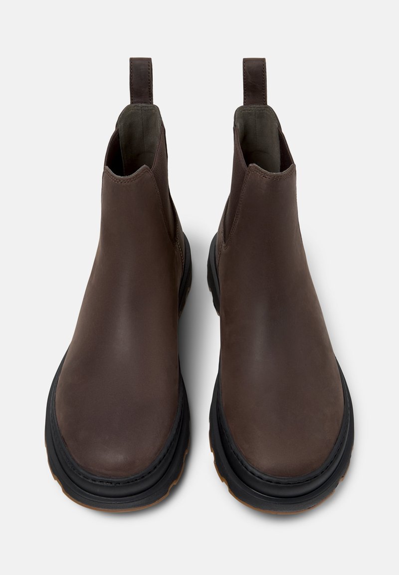 Bottines Chelsea en cuir marron avec une finition lisse, des panneaux élastiques sur les côtés, des languettes et une semelle en caoutchouc noir texturé.