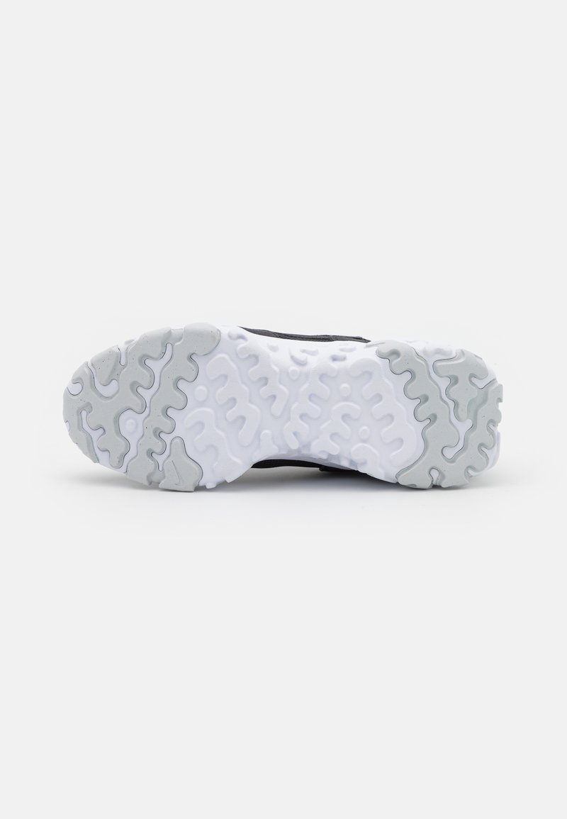 Suela de zapato atlético negra con una base de goma blanca que presenta patrones de respuesta ondulados y acentos grises. Superficie texturizada para un mejor agarre y estabilidad.
