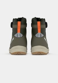 Une paire de bottes de sport vikings vertes avec des languettes orange, des patchs réfléchissants au talon, des semelles beige, vues de dos sur un fond blanc.