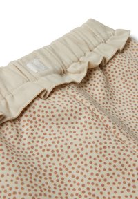Světlý béžový materiál s malými rezavými tečkami. Rukávci s elastickým pasem, obsahuje malou bílou štítku připevněnou. Měkká struktura.