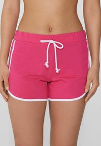 Shorts de bain roses en tissu doux, avec une taille à cordon de serrage et un liseré blanc le long de l'ourlet et des coutures latérales.