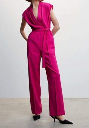 Combinaison fuchsia avec un profond décolleté en V, manches courtes, taille ceinturée et pantalons à jambes larges. Tissu lisse et design minimaliste.