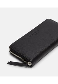 Czarny skórzany portfel o fakturowanej powierzchni, z zamkiem na suwak dookoła i paskiem na nadgarstek. Subtelne logo marki wytłoczone z przodu.