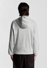 Felpa grigia con cappuccio, dal texture morbido, caratterizzata da maniche lunghe e una vestibilità casual. La vista posteriore mostra un design semplice senza decorazioni.