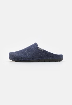 Navy wool slipper with a soft texture, open back, rounded toe, and contrasting black rubber sole; features a small logo tag on the side.