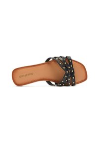 Sandale glissante en cuir noir avec des brides croisées ornées de clous dorés. La semelle est de couleur caramel, de forme rectangulaire et avec un logo en relief.