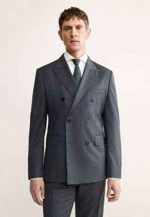 Grau melierter Double-Breasted-Sakko mit Reverskragen, zwei vorderen Taschen und Knopfdetails; kombiniert mit einem weißen Hemd und einer grauen Krawatte.