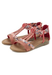 Koraal kleurige sandaal met bloemaccenten, metallic studs en een gevoerde binnenzool. Voorzien van meerdere banden en een lage wiggenhak voor comfort.