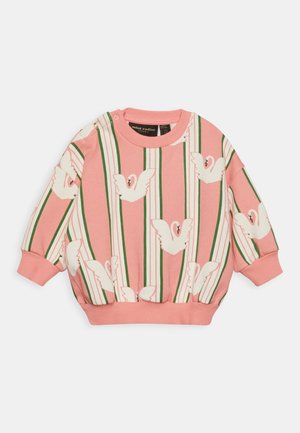 Różowy sweter z białym wzorem łabędzia, zielonymi i białymi paskami, ściągaczami na mankietach oraz okrągłym dekoltem. Wyposażony w boczne napy dla łatwego zakładania.