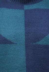 Πουλόβερ με υφαντό πλεκτό υφή και γεωμετρικό σχέδιο σε βαθιές αποχρώσεις του μπλε και τιρκουάζ, με ριμπ ύφανση στο λαιμό και απαλό φινίρισμα.