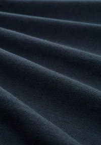 Tissu texturé bleu foncé avec des plis horizontaux, fabriqué à partir d'un matériau doux et tricoté. Couture fine visible et coloration uniforme.